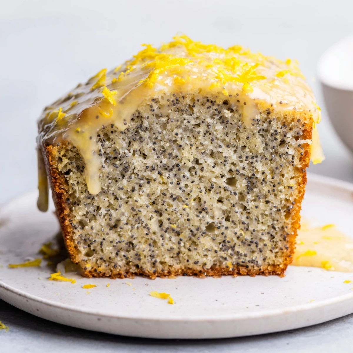 Warm, golden Glazed Lemon Poppy Seed Cake, sliced and ready to enjoy with a tangy lemon drizzle.