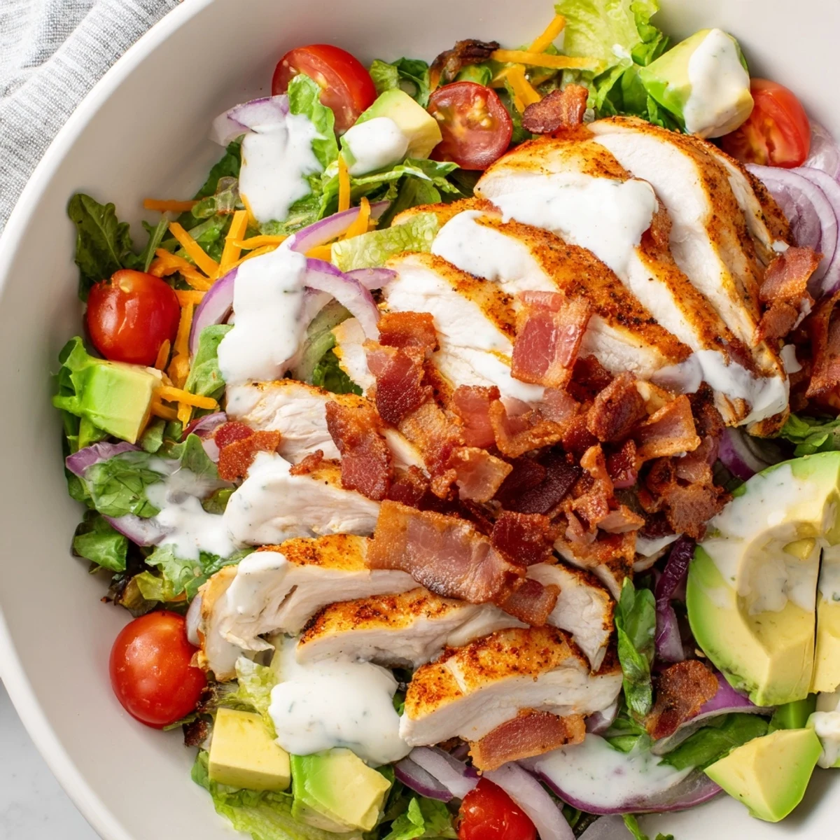 A colorful bowl of Crispy Bacon Chicken Salad, showing juicy chicken and creamy ranch dressing.
