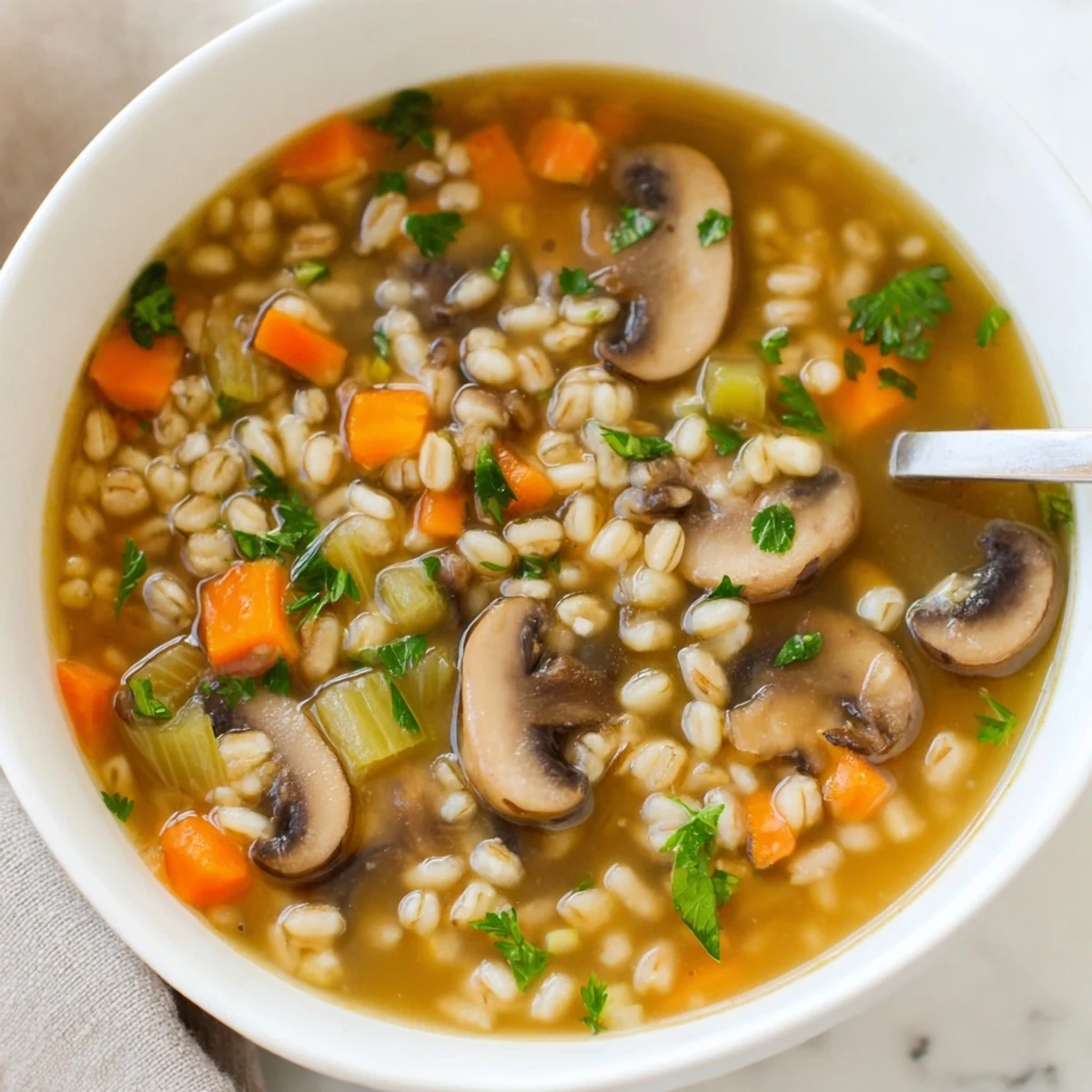A warm bowl of homemade Mushroom and Barley Soup, filled with tender sliced mushrooms and chewy pearl barley in a savory broth.