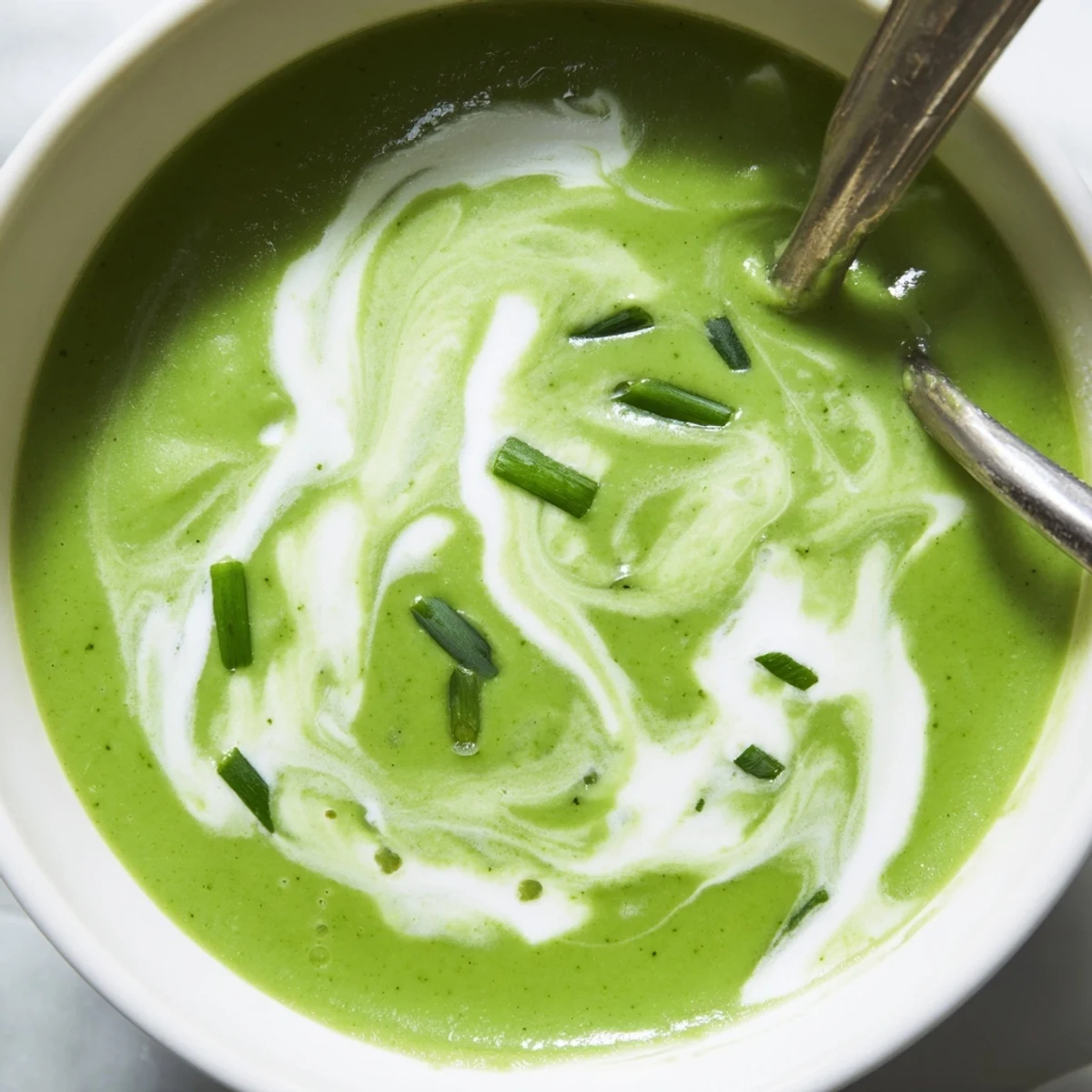 Close-up of velvety creamy broccoli soup in a white bowl, highlighting vibrant green broccoli florets.