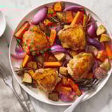 Close-up of savory Honey-Glazed Chicken recipe with colorful, caramelized root vegetables on baking sheet.