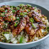 A hearty serving of Egg Roll Bowls with Chicken and Cabbage, drizzled with chili crisp and paired with fluffy white rice.