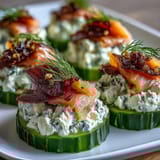 Elegant appetizer: cool cucumber slices layered with rich cream cheese and delicate smoked salmon, finished with bright lemon zest.  
