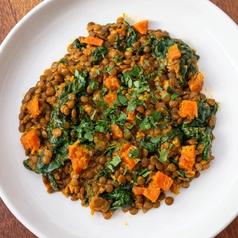 Steaming bowl of Lentil and Spinach Curry, a vibrant vegan dish garnished with cilantro.