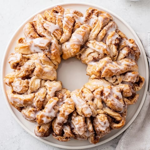 Fluffy cinnamon roll pull-apart wreath, golden brown and glistening with a sweet vanilla glaze.