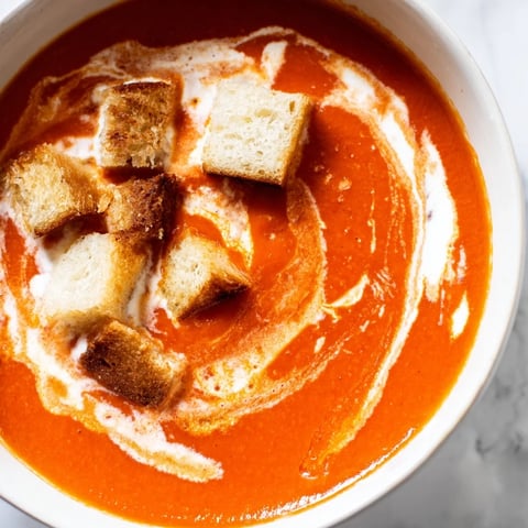 A bowl of roasted tomato soup topped with golden, crunchy homemade croutons.