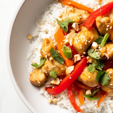 A close-up view of a flavorful Sesame Ginger Rice Bowl, drizzled with savory sauce and garnished.