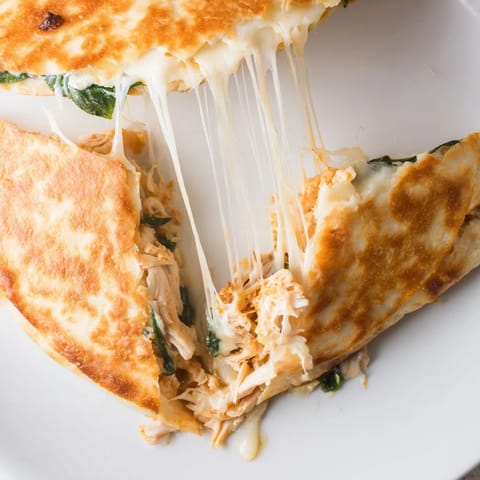 Sliced Chicken and Spinach Quesadilla served with a dollop of sour cream and salsa.