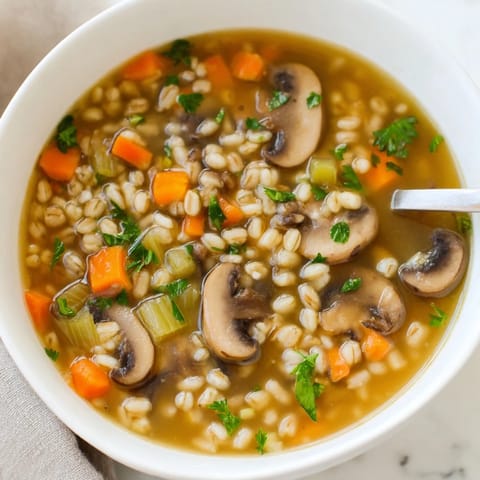 A warm bowl of homemade Mushroom and Barley Soup, filled with tender sliced mushrooms and chewy pearl barley in a savory broth.