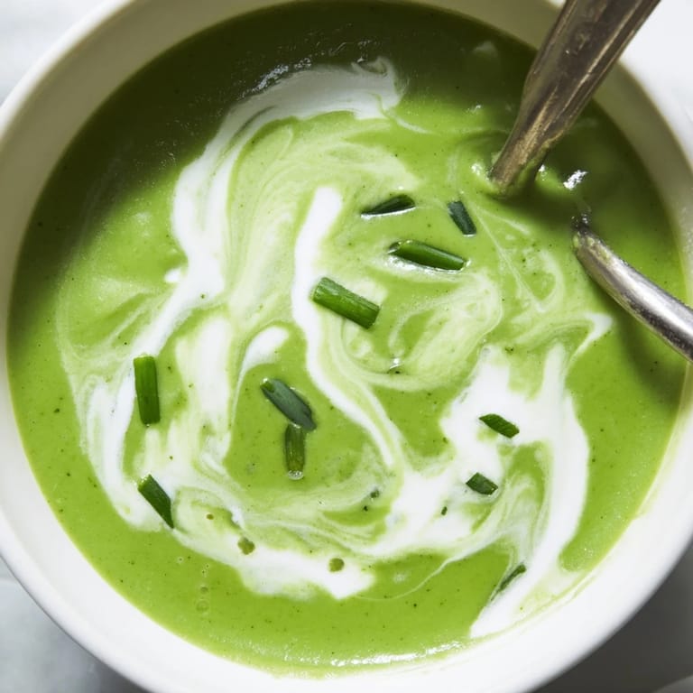Close-up of velvety creamy broccoli soup in a white bowl, highlighting vibrant green broccoli florets.