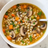 A warm bowl of homemade Mushroom and Barley Soup, filled with tender sliced mushrooms and chewy pearl barley in a savory broth.