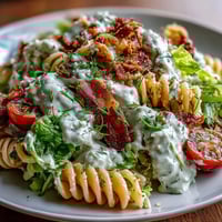 Vibrant BLT pasta salad with crispy bacon, juicy tomatoes, and creamy avocado ranch dressing, perfect for summer gatherings.